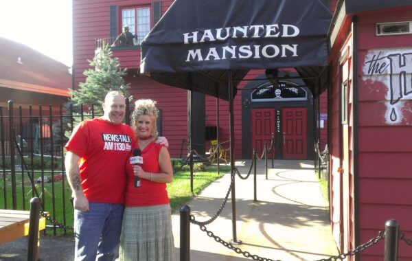 Dave Schrader & Jodi in front of the not so haunted house at the fair